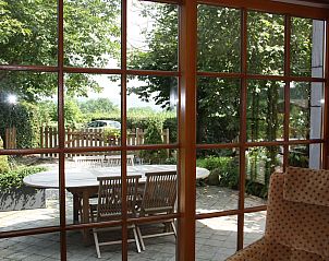 View from Holiday home am Teich in Hombourg, Ardennes, shows a sunny terrace with wooden table and chairs surrounded by green nature.
