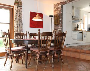 Cozy dining room in Holiday home am Teich, Hombourg, Ardennes, with wooden table, chairs and open kitchen for a cozy stay.