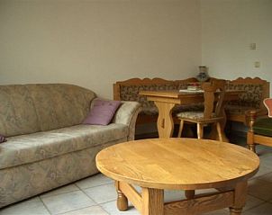 Cozy sitting area in vacation home Zur Krombisch, Elsenborn, Ardennes, with wooden furniture and soft sofa.