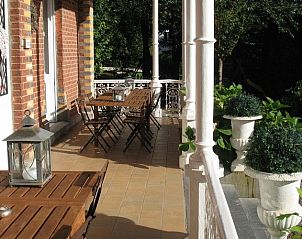Zonnig terras van Kasteelvilla Santa Maria in Spa, Ardennen, Belgi, met uitnodigende zitplaatsen en groene omgeving.