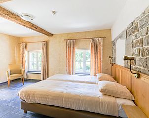 Sfeervolle slaapkamer in vakantiehuis ARD198, Aywaille, Ardennen, Belgi met rustieke stenen muur en uitzicht op de groene omgeving.