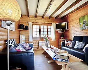 Gezellige woonkamer in La Pomme de Pin, Fraiture, Ardennen, met houten interieur en comfortabele zithoek.