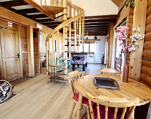 Sfeervolle binnenruimte van La Pomme de Pin in Fraiture, Ardennen, met houten trap en speeltafel.