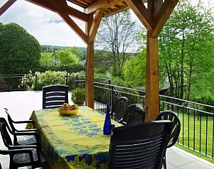 Cozy dining area on the veranda of Les Gronsarts Vencimont vacation home overlooking nature in Vencimont, Belgium.