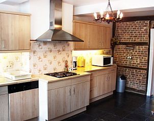 Modern kitchen in Les Gronsarts Vencimont cottage with wooden cabinets and brick details in Vencimont, Ardennes.