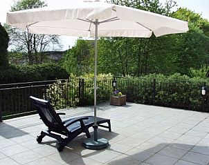 Sunny terrace with lounger and parasol at Les Gronsarts Vencimont vacation home in the green Ardennes, Vencimont, Belgium.