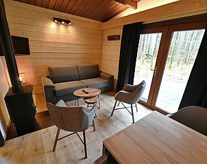 Gemtliches Wohnzimmer im Cottage in Oignies-en-Thirache, Ferienhaus in den Ardennen, Belgien, mit Blick auf den Wald durch groe Fenster.