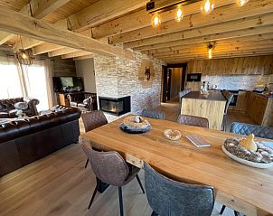 Cozy interior of Le Refuge vacation home in Achouffe, Ardennes, Belgium, with wooden interior and fireplace.