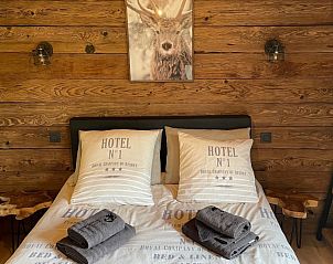 Cozy bedroom in Le Refuge cottage, Achouffe, Ardennes, with rustic wooden walls and comfortable beds for a relaxing stay.