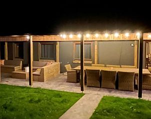 Illuminated veranda of vacation home Le Refuge in Achouffe, Ardennes, Belgium, with comfortable seating and a cozy ambiance.