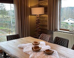 Cozy indoor area of vacation home Le Refuge in Achouffe, Ardennes, Belgium with wooden dining table and atmospheric lighting.