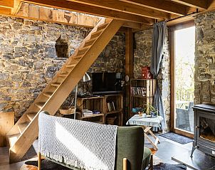 Gemtliches Interieur des Ferienhauses in Durbuy, Ardennen, mit rustikalen Steinwnden und einer Holztreppe zum Obergeschoss.