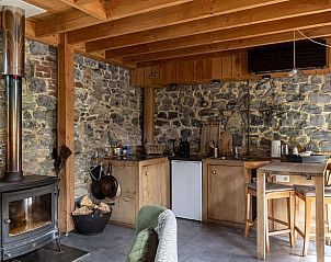 Gemtliche Einrichtung des Ferienhauses in Durbuy, Ardennen, mit rustikalen Steinwnden und einem gemtlichen Holzofen.