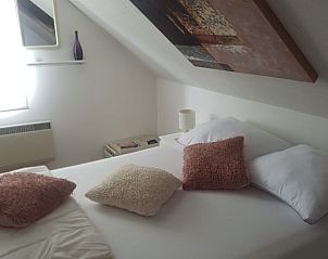 Cozy attic room in Holiday Home Ardennes, Durbuy, Belgium with comfortable beds and unique roof slope for a cozy atmosphere.