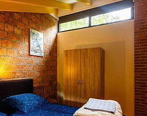 Sfeervolle slaapkamer in Vakantiehuis in Izier, Ardennen, Belgi met bakstenen muur en houten kast.