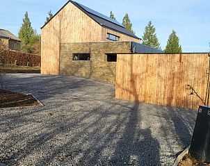 Huisje in Grandmenil, vakantiehuis in de Ardennen, Belgi met moderne houten gevel en ruime oprit omringd door natuur.