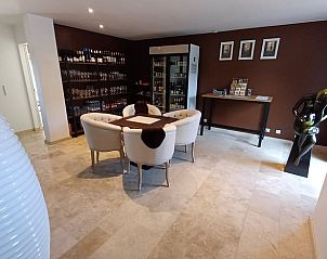 Stijlvolle binnenruimte in Vakantiehuis in Ereze, Ardennen, met comfortabele zithoek en wijncollectie, ideaal voor ontspanning.