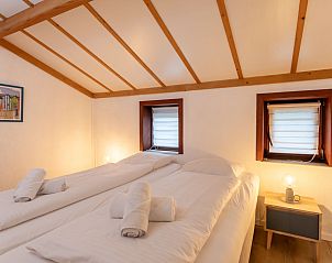 Gemtliches Schlafzimmer im Ferienhaus Strandhuis in Bredene an der belgischen Kste mit Holzbalkendecke und gemtlicher Beleuchtung fr einen entspannten Aufenthalt.