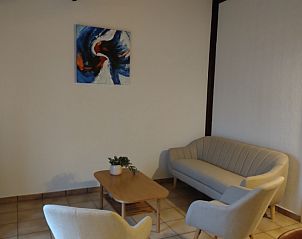 Gemtliches Wohnzimmer des Duinenhuisje, einem Ferienhaus in Bredene an der belgischen Kste, mit komfortabler Sitzecke und moderner Kunst an den Wnden.