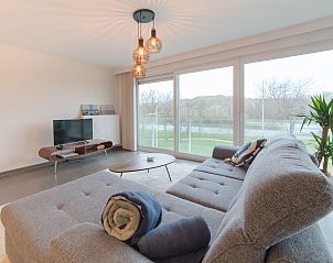 Cozy living room of Apartment Ocean in Bredene, Belgian coast, overlooking nature through large windows.