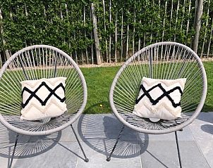 Zee en polder vakantiehuis tuin met comfortabele stoelen en kussens in Lombardsijde, Belgi.