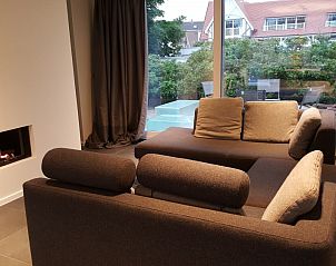 Cozy living room with fireplace in bungalow in Oostduinkerke, Belgian coast, overlooking terrace.