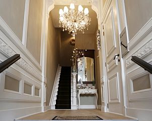 Elegant entrance to De Zeebries apartment in Ostend with chandelier and staircase.