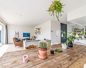 Lichte woonkamer van Vakantiehuis Villa Vosseslag in De Haan, Belgische kust, met een rustieke tafel en groene planten.
