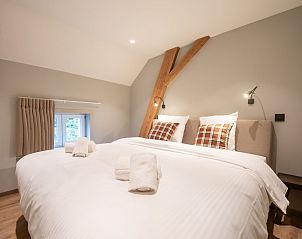 Gezellige slaapkamer in Vakantiehuis Huyze Ter Bercken, De Haan, Belgische kust. Comfortabele bedden en rustieke elementen voor een ontspannen verblijf.